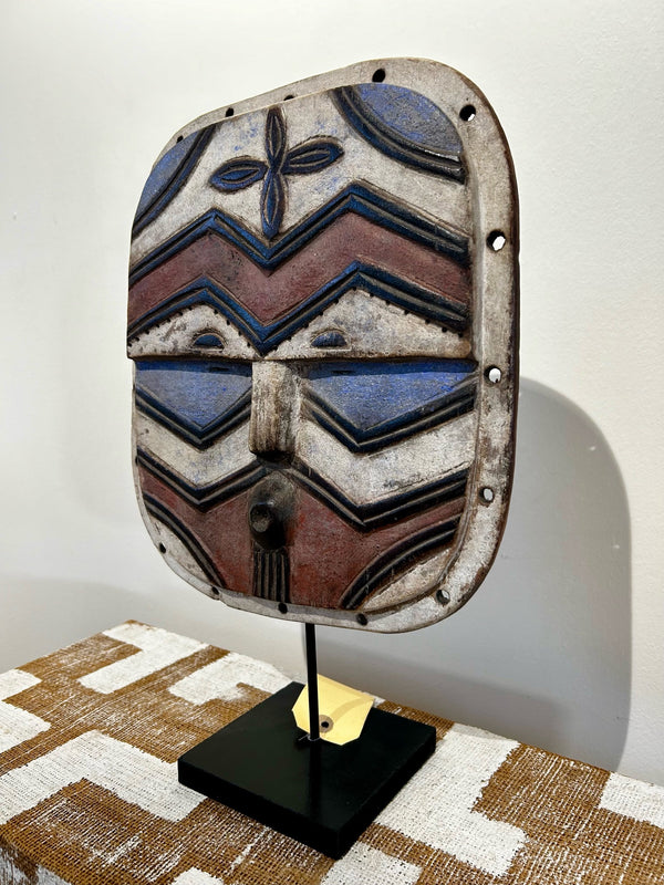 Butterfly mask from Teke Bateke tribe, Congo-Zaire, featuring intricate carvings and multicolor patterns, displayed on a stand at Rogl Souvenirs & Gallery, African art gallery.
