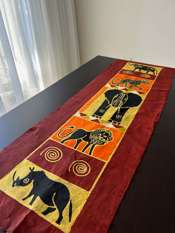 African batik table cloth featuring the "Big 5" wildlife with lion, leopard, elephant, rhino, and buffalo, hand-painted on high-quality cotton fabric, displayed on a dining table.