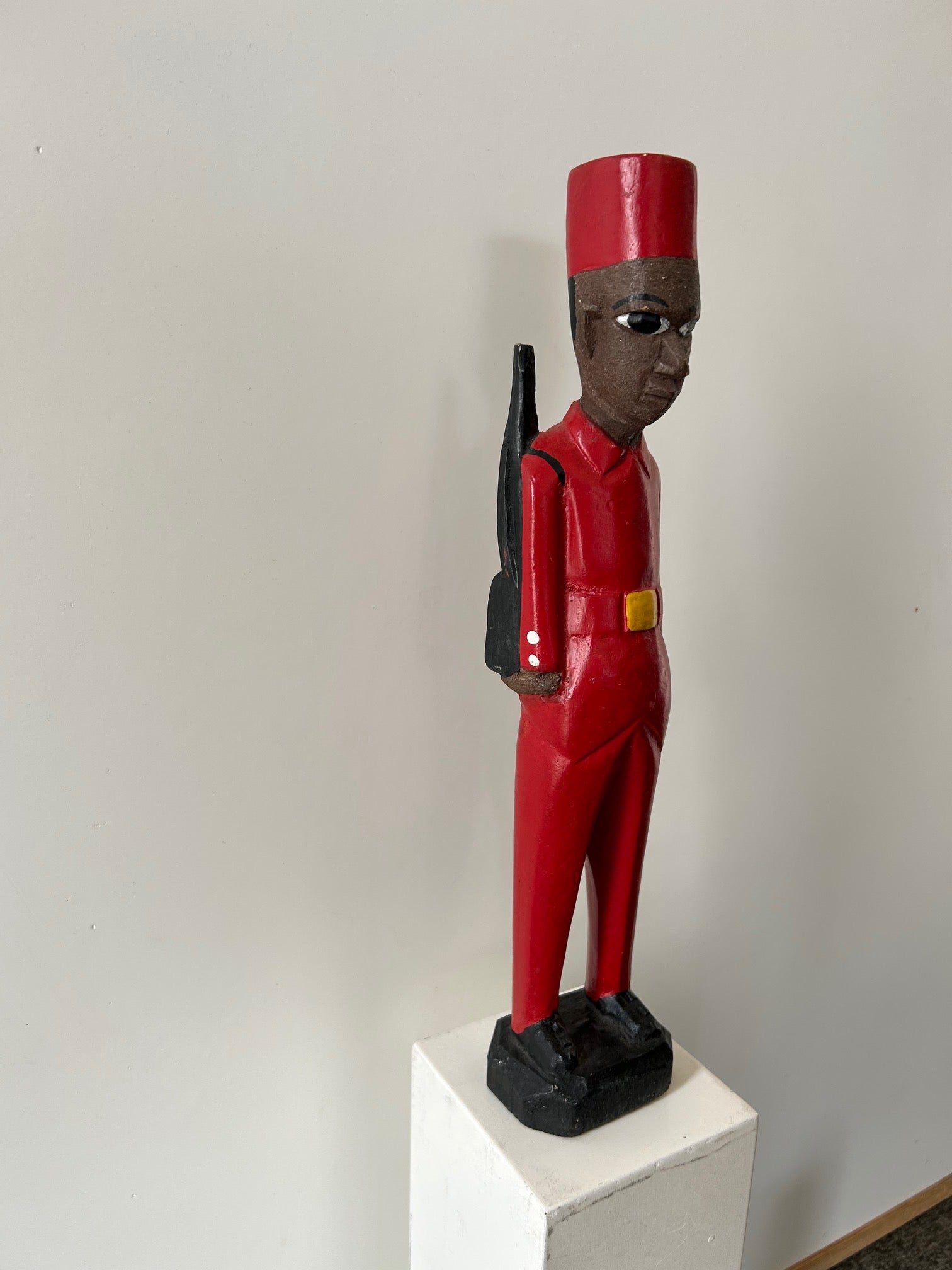 African colonial figure sculpture of a mercenary in red uniform with a rifle, displayed at Rogl Souvenirs & Gallery.