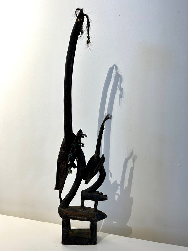 Female Chiwara mask from the Bambara tribe in Mali, depicting an antelope with a child on its back, symbolizing fertility and motherhood, displayed in Rogl Souvenirs & Gallery.