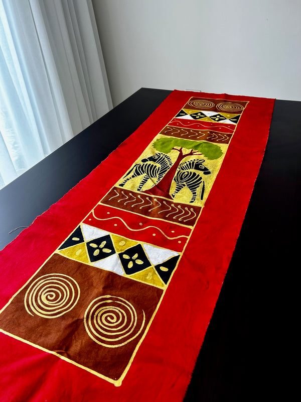 Batik table cloth with vibrant red background featuring two intricately detailed zebras, African art design, Rogl Souvenirs & Gallery.