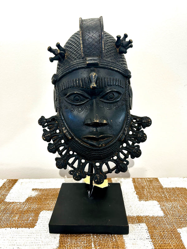 Bronze Ife tribe mask from Benin with intricate patterns and royal crown, displayed on a stand at Rogl Souvenirs & Gallery, African art gallery.