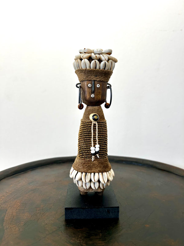 Gold Namji doll sculpture from Cameroon adorned with beads and cowrie shells, representing fertility and motherhood.