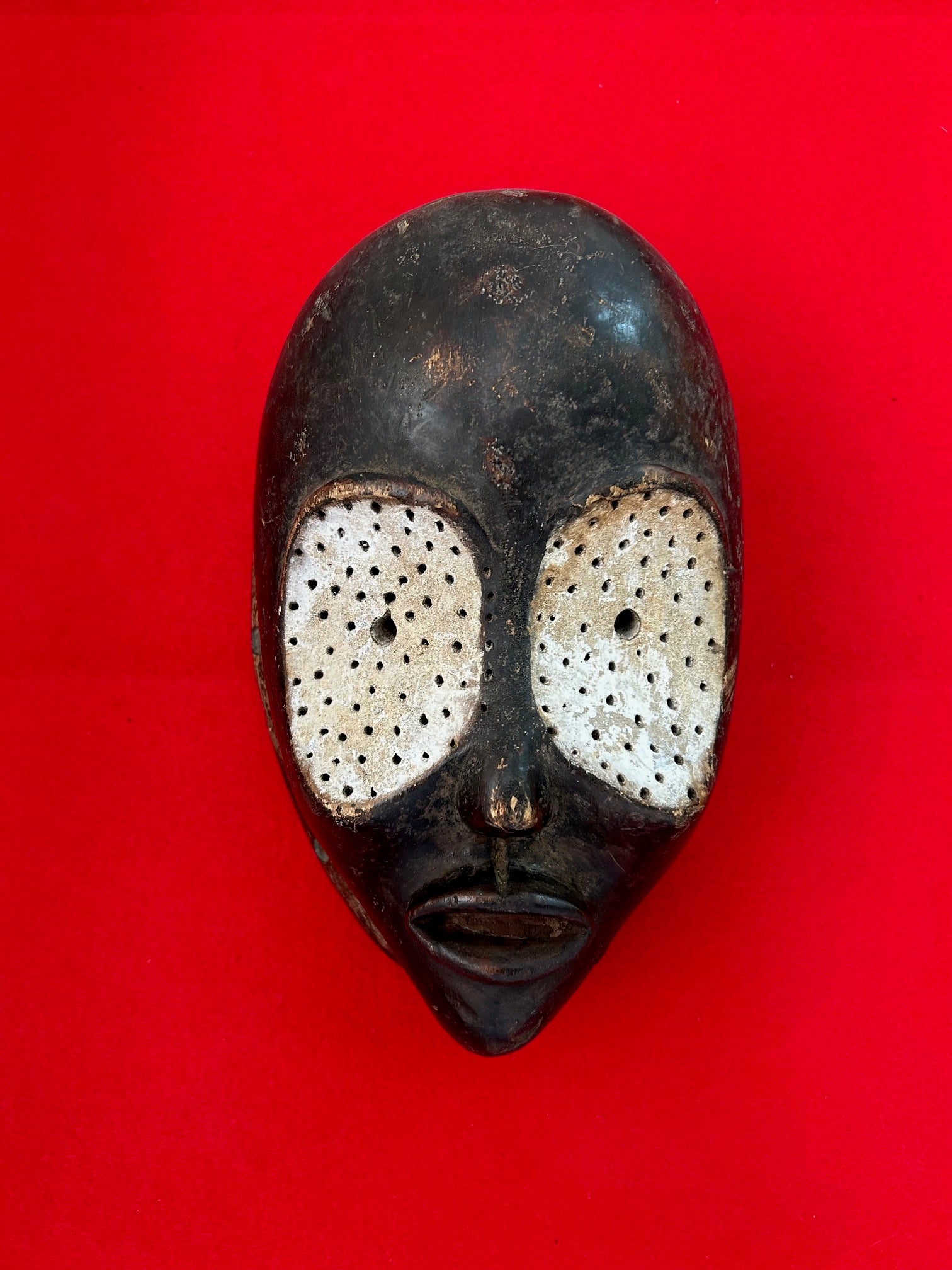 Owl Mask from the Dan tribe in Ivory Coast, featuring abstract design with white chalk accents on dark wood, symbolizing wisdom and knowledge.