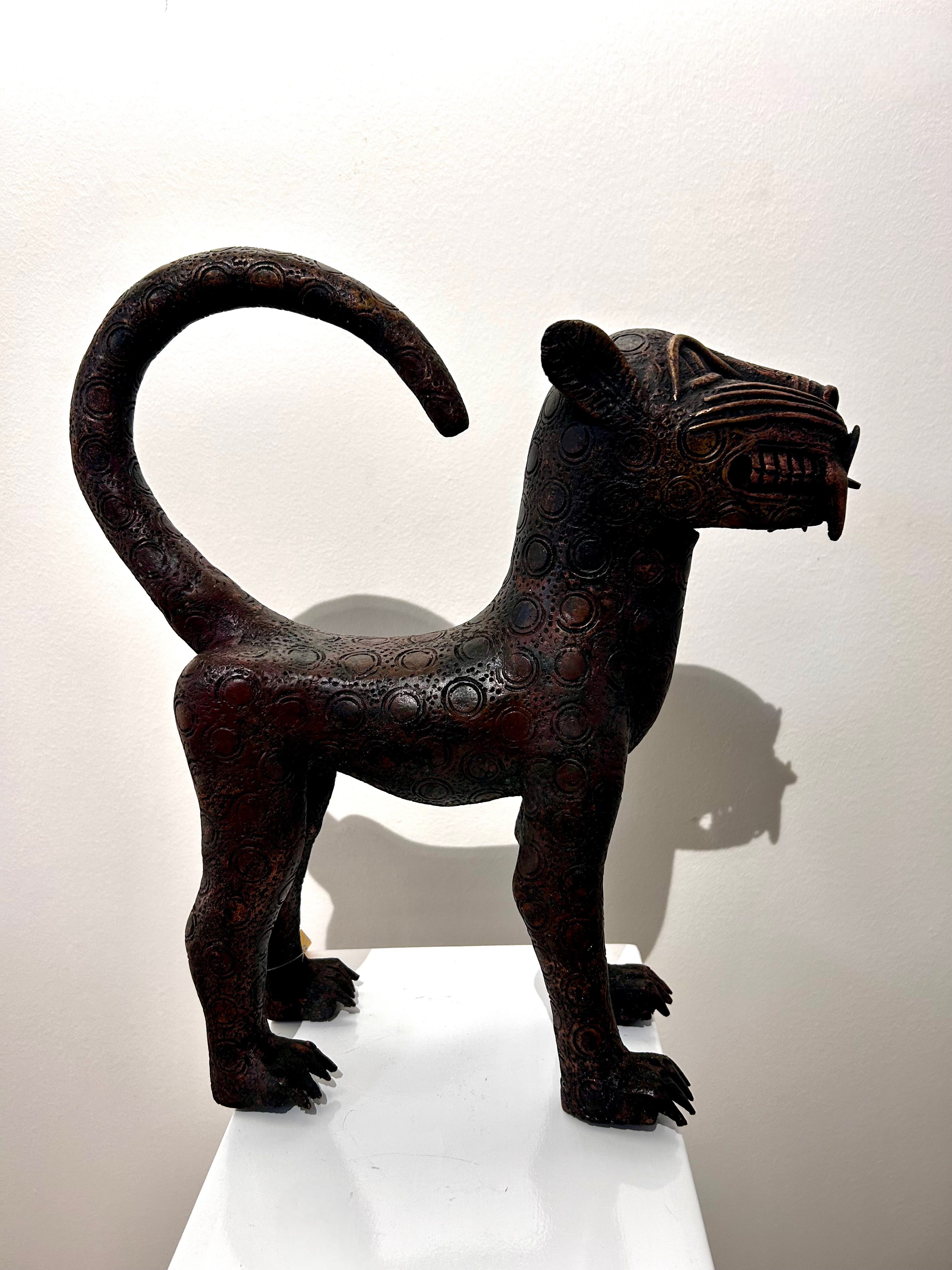 Handcrafted bronze leopard sculpture with intricate patterns and raised tail on display.