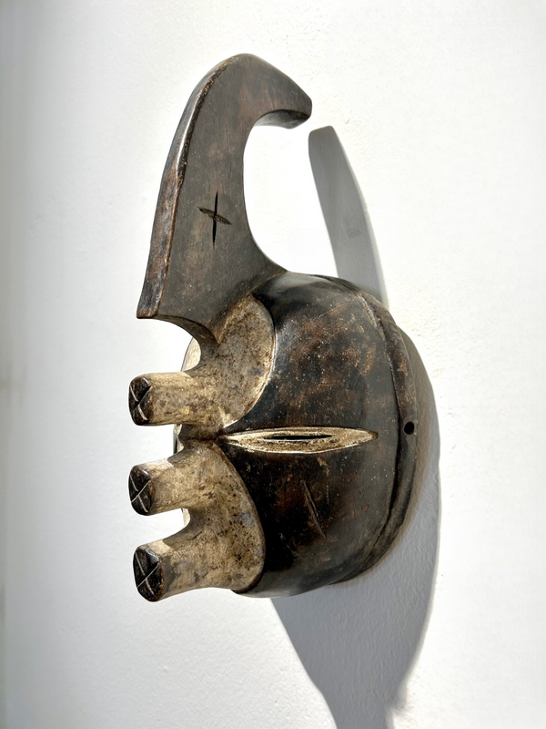 Ijo mask from Nigeria, abstract art with unique shape, dark wood, black and white colors, used in rituals by Ijo people, displayed at Rogl Souvenirs & Gallery.