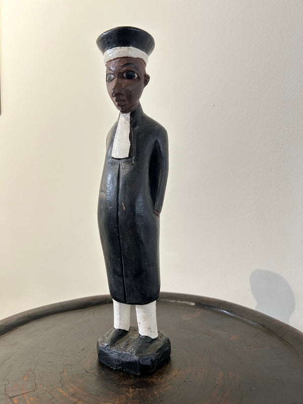 Wooden colonial figure sculpture from Ivory Coast depicting a judge, hand-carved with black and white colors, symbolizing historical colonialism and cultural exchange.