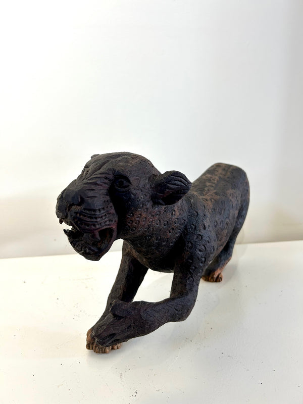 Wood sculpture of a leopard in an alert stance, showcasing intricate details and dark brown color, crafted in Namibia, available at Rogl Souvenirs & Gallery.