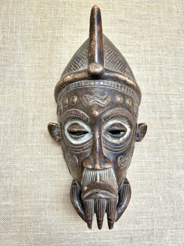 Bearded Elder mask from the Lulua tribe, featuring intricate carvings and facial markings, symbolizing wisdom and authority, Congo-Zaire.