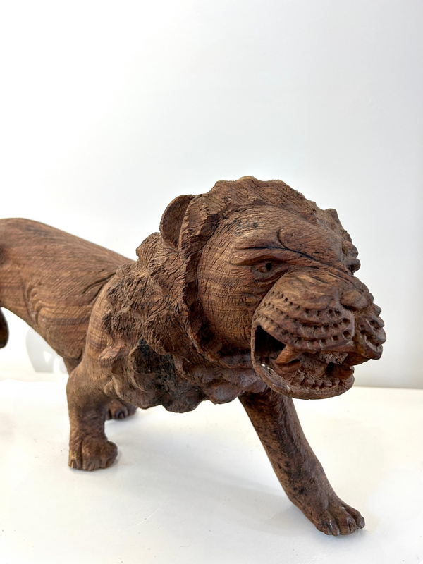 Handcrafted wooden sculpture of a male lion with intricate carvings, showcasing lifelike texture and piercing eyes, from Rogl Souvenirs & Gallery.