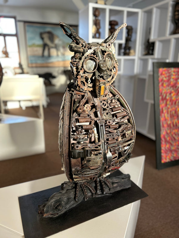 Robo-Owl sculpture made from metal workshop items, featuring screws, gears, and springs, displayed in Rogl Souvenirs & Gallery, African art gallery.