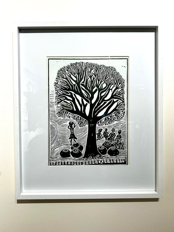 Limited edition black and white linocut print by artist Kapanda, depicting women collecting marula fruits under a large Marula tree in rural Namibia, showcasing traditional life.