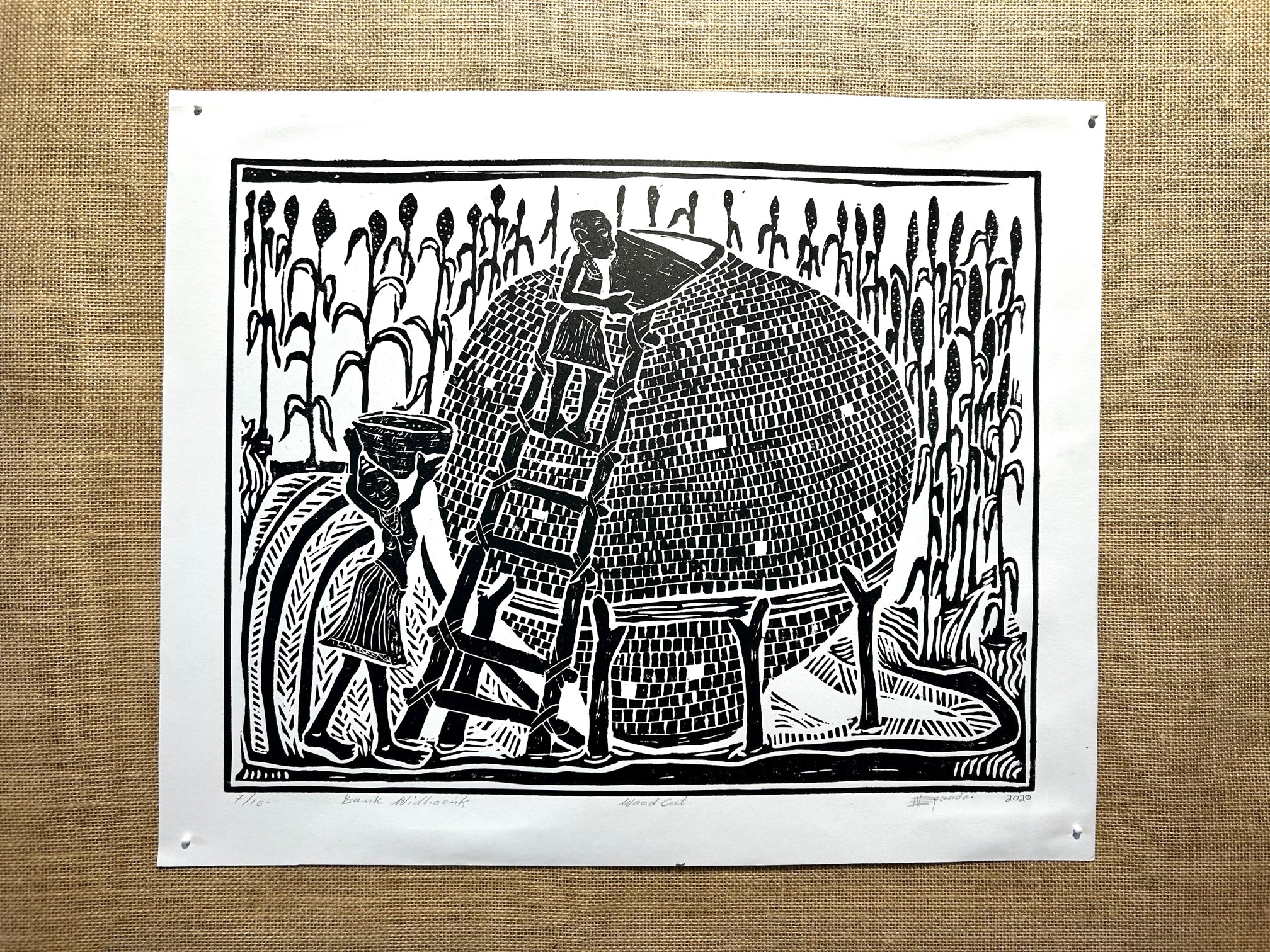 Black and white woodcut print of Namibian villagers filling a traditional grain storage basket with mahango, showcasing cultural heritage and agricultural practices.