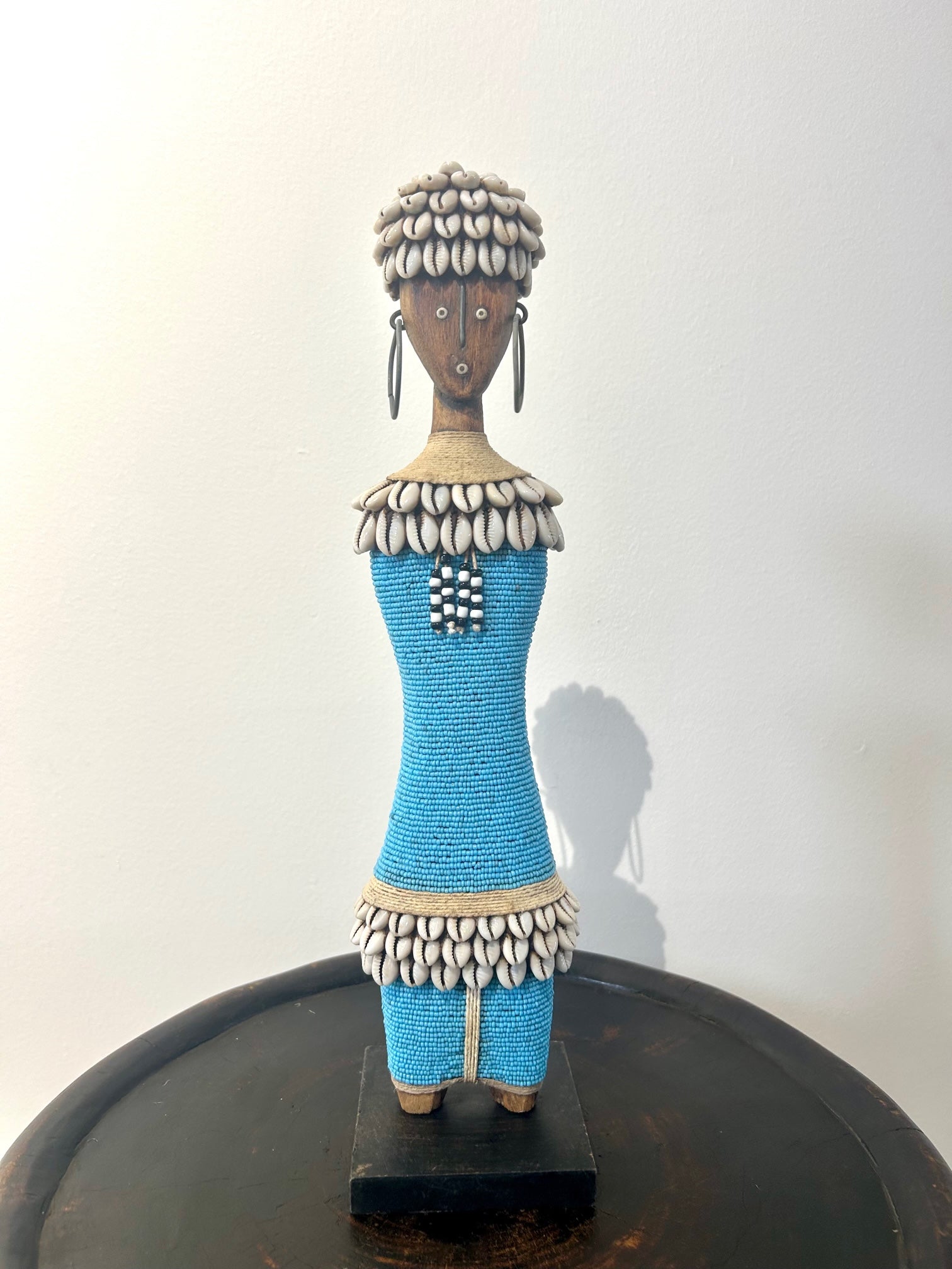 Turquoise Namji doll sculpture adorned with beads and cowrie shells, representing fertility and motherhood, from the Namji tribe in Cameroon.