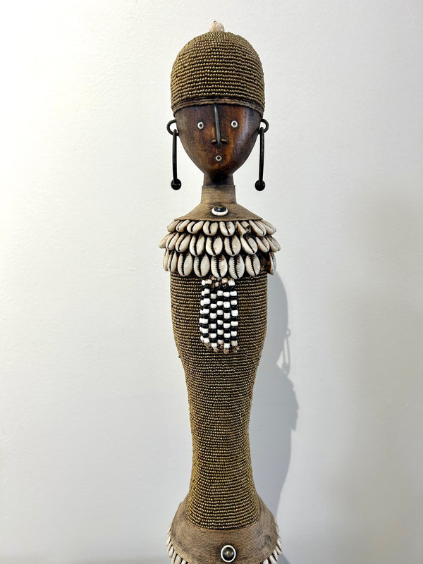 Beaded Namji doll in gold with intricate cowrie shell and bead adornments, representing fertility and motherhood from the Namji tribe, Cameroon.