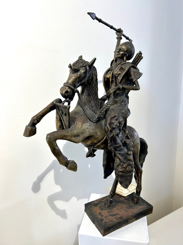 Bronze sculpture of Princess Yennenga from the Mossi tribe in Burkina Faso, riding a horse and wielding a spear, displayed at Rogl Souvenirs & Gallery.