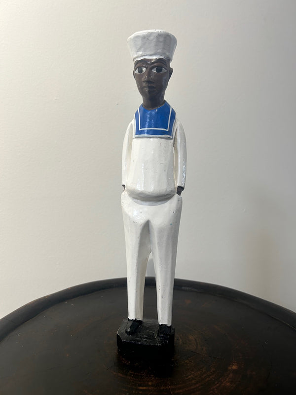 Colonial figure sculpture of a sailor from Ivory Coast, hand-carved wooden art piece with blue and white attire, representing historical colonial era, displayed at Rogl Souvenirs & Gallery.