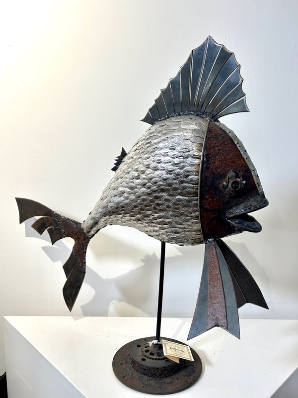 Spoon fish sculpture made from scrap metal and cutlery, showcasing intricate details and metallic grey textures, handcrafted by artist Ras from Namibia, displayed at Rogl Souvenirs & Gallery.