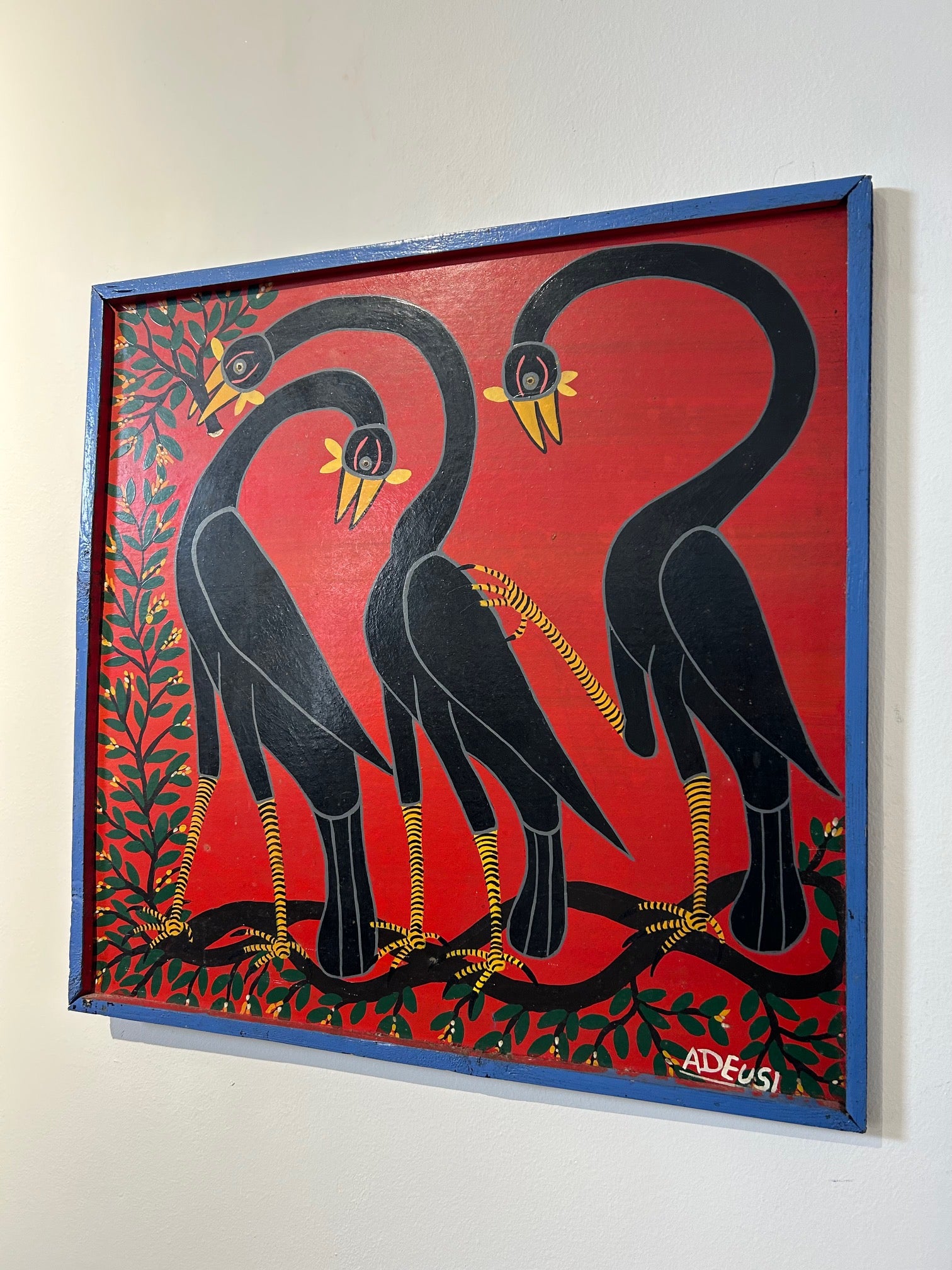 Tingatinga painting of three black birds with elongated necks, vibrant colors, and intricate patterns by Adeusi, displayed in a standard frame.
