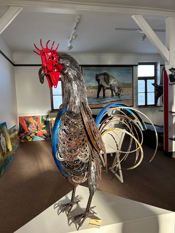 Majestic rooster sculpture made from upcycled materials including scrap metal and bicycle parts, displayed in Rogl Souvenirs & Gallery, showcasing artistic innovation and sustainability.