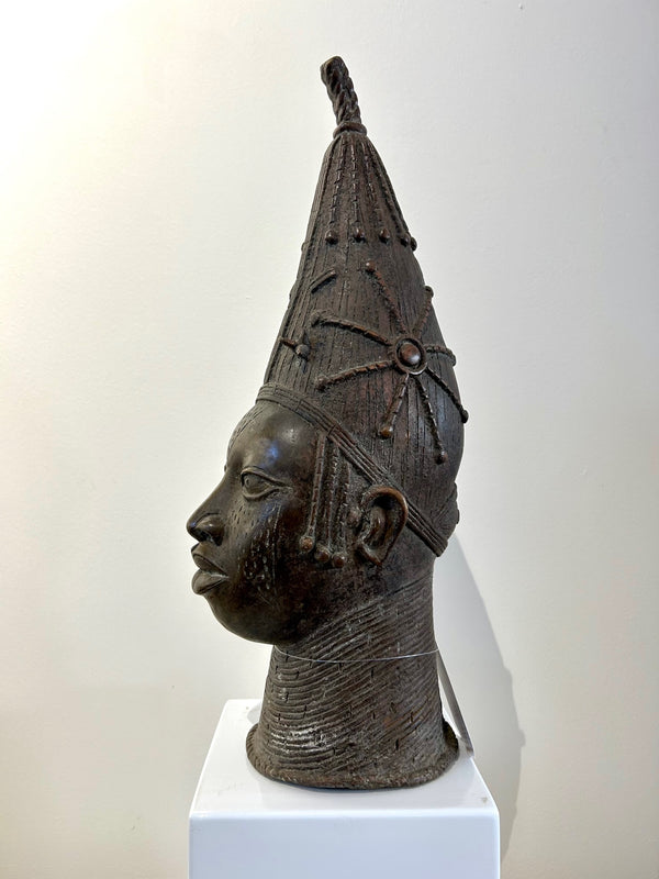Bronze head sculpture of a Yoruba queen from Nigeria, featuring intricate crown and jewelry, displayed at Rogl Souvenirs & Gallery.