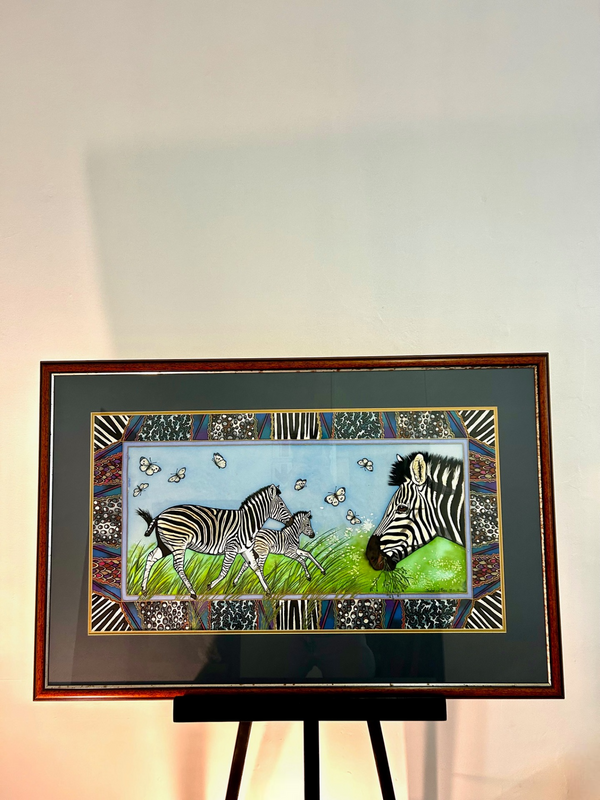 Painting "Serenity in Reflections" by Isabel, featuring a mother zebra and foal using paint under glass technique, vibrant colors, and intricate patterns, displayed in a gallery frame.